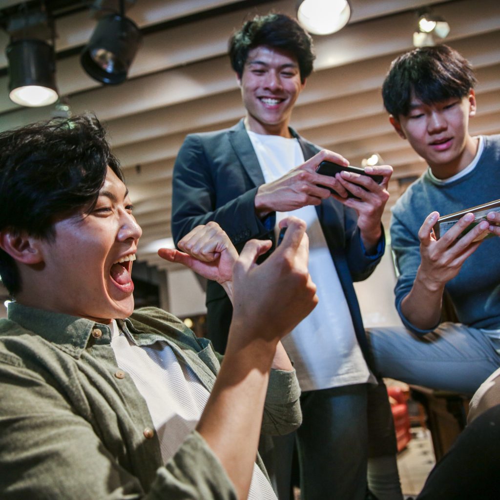 Young friends playing mobile game in cafe