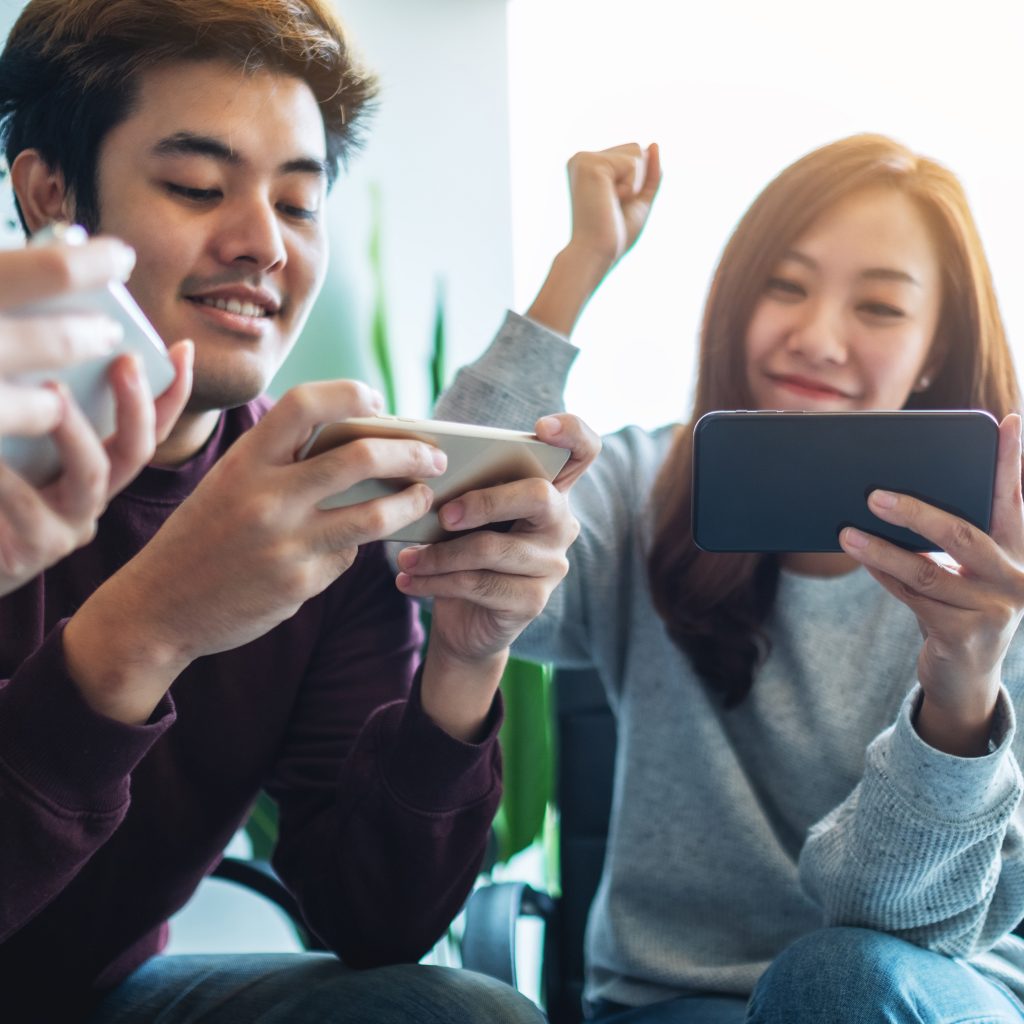 A group of young people having fun and celebrating while watching and playing games on mobile phone together