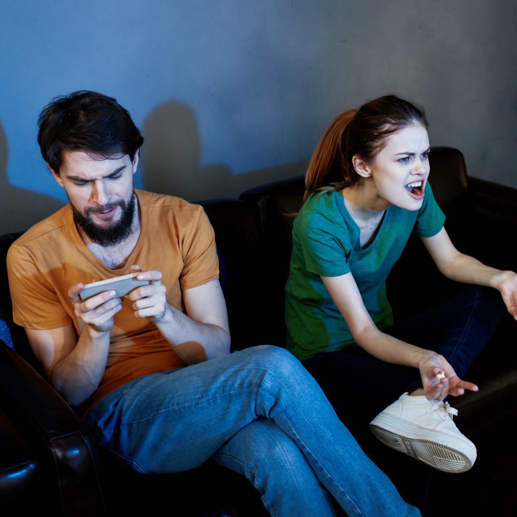 A woman and a man with popcorn on a leather sofa indoors watching TV in the evening. High quality photo